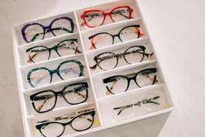 A white display box containing multiple pairs of glasses in different colors and styles.