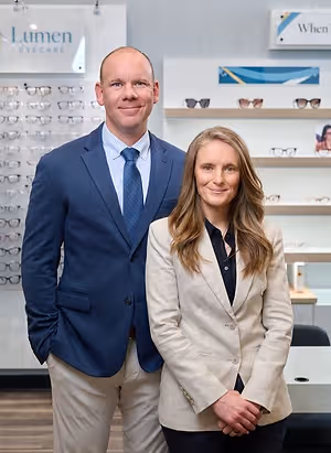 A man and a woman standing next to each other in front of an optician's shop