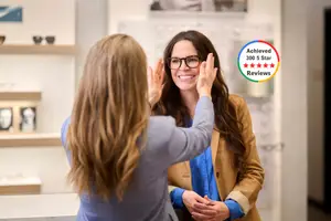 A smiling woman with glasses getting her glasses adjusted by an optician
