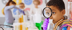 A young boy is using a magnifying glass in a science lab.