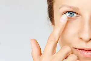 Close up of a woman with blue eyes putting in a contact lens
