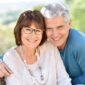 An elderly couple sitting close to each other with smiling faces