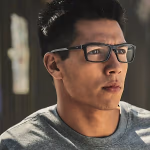 Man wearing glasses looking to the left with a serious expression