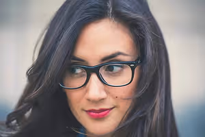 A woman with black hair and glasses smiling for a photo
