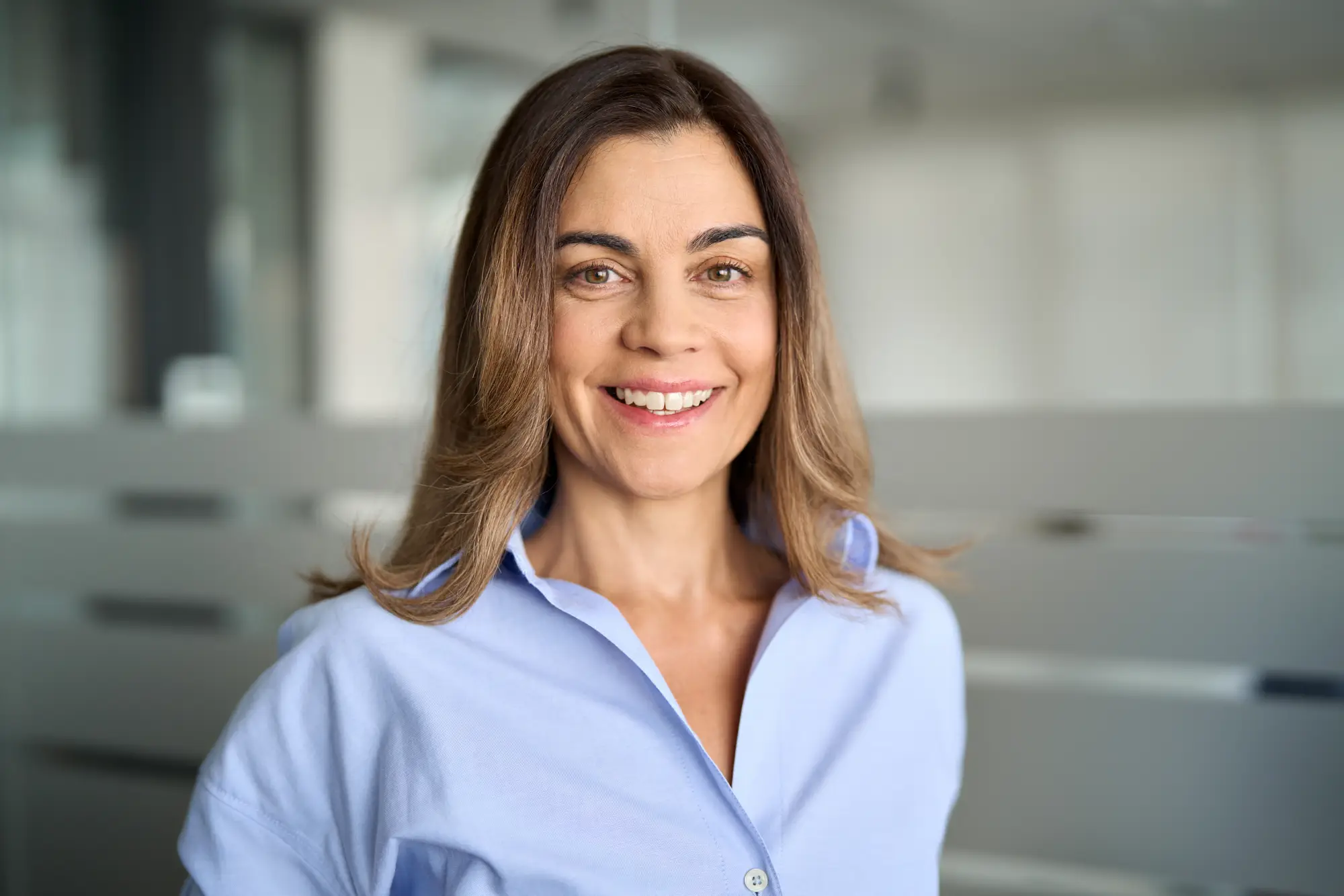 Image of a smiling woman in a blue shirt standing in an office