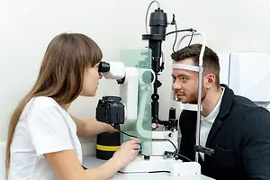 A man getting his eye examined by a woman in a white coat