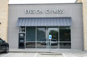 An optical store with the sign 'Eyes on Cypress' above the glass door.