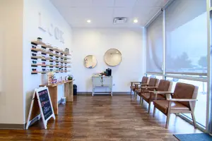 A photo of an interior of a medical clinic with chairs and a table with items on top