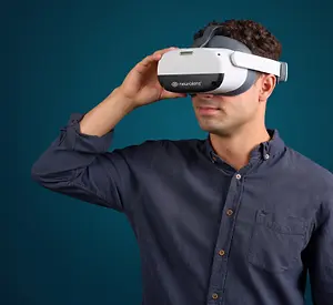 A man in a blue shirt is using a virtual reality headset in a studio.