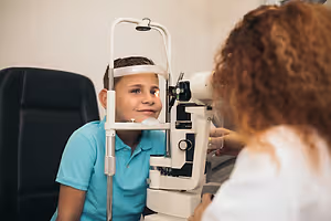 Child receiving an eye examination with a slit lamp microscope from an optometrist