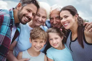 Three generations of a family are smiling and posing for a picture together