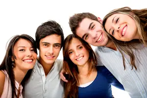 Five young adults are smiling and posing for a group photo with their heads close together