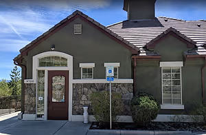 The front of a house with stone wall, brown door, and sign indicating reserved parking