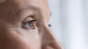 Close up of a woman's face with a side profile view, showing her eye and nose, and some wrinkles on her skin.