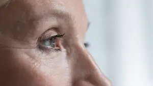 Close up of a woman's face with a side profile view, showing her eye and nose, and some wrinkles on her skin.