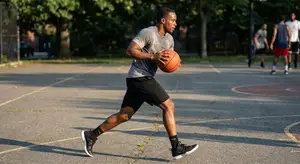 A man running on a basketball court while holding a ball