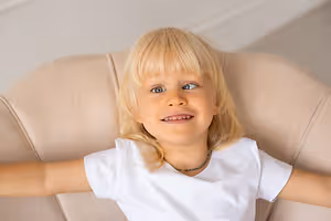 Smiling blonde child reclining in a chair with arms outstretched