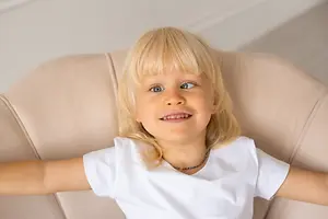 Smiling blonde child reclining in a chair with arms outstretched