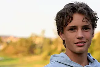 Smiling male with curly hair in a blue hoodie