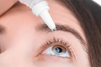 Woman applying eye drops to her eye