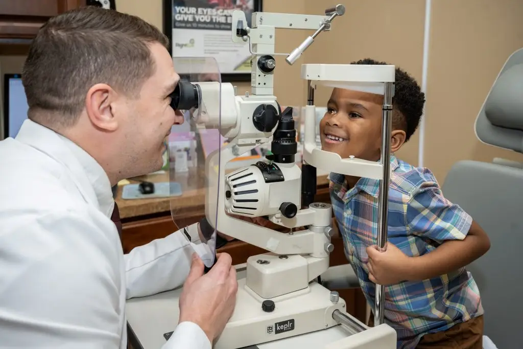 A young boy is having his eyes examined by an eye doctor.