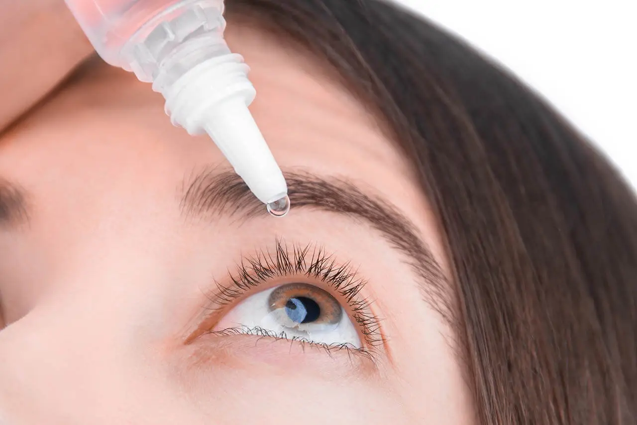 Woman applying eye drops with a dropper bottle to her eye.
