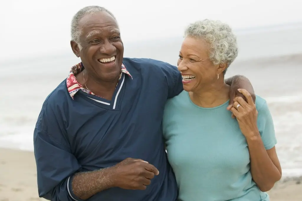 Happy elderly couple standing on the beach and smiling at each other
