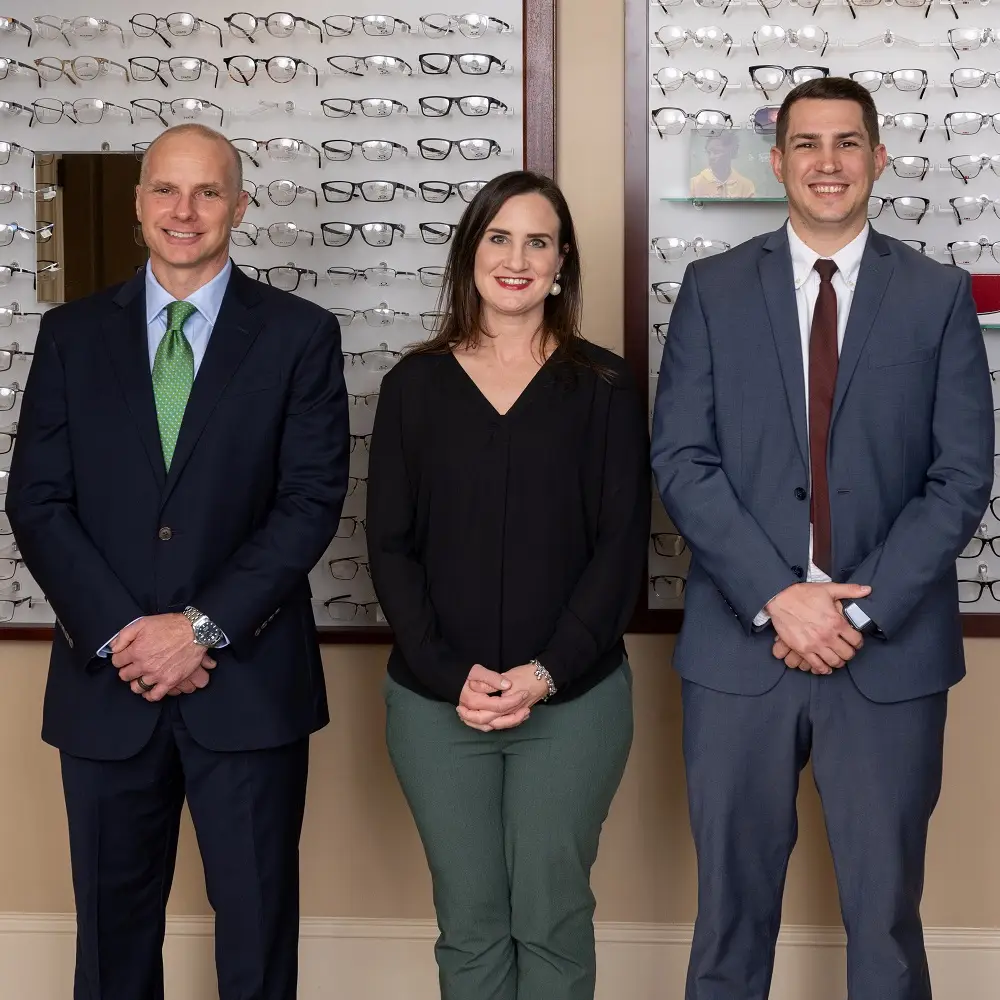 Three people standing in front of a wall of glasses