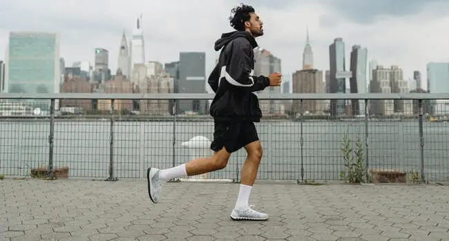 A man running on a path with a city skyline in the background