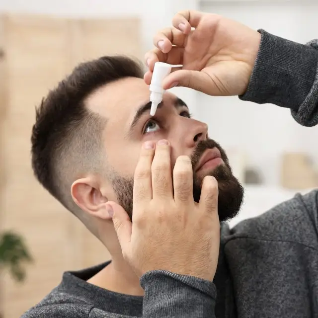 Close up of a man putting in eye drops