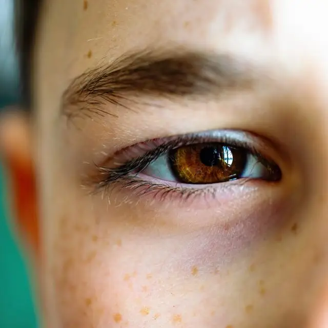 Close-up of a young person's eye with brown iris and eyelashes