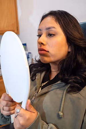 A woman looking into a mirror with her lips puckered