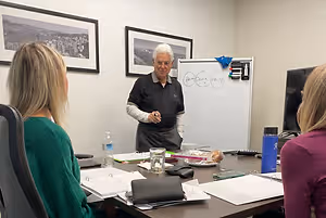 A man is teaching a business seminar to a group of women