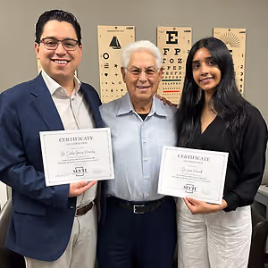 Three people are posing for a photo holding certificates and smiling at the camera.