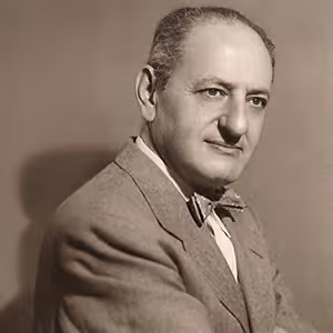 A black and white photo of an older man with a bow tie and a suit.