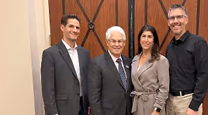 Four people posing for a photo in front of a door