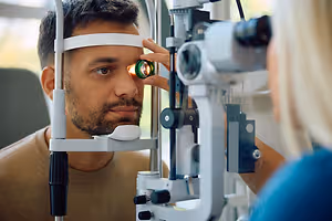 A man getting his eyes examined by a female doctor in a medical setting.