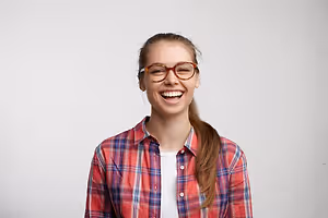 Young woman with glasses and a plaid shirt smiling for the camera
