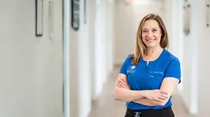 Dr. Amy Cline, an eye care doctor, standing in a hallway and smiling at the camera