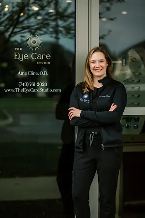 A woman standing outside of The Eye Care Studio building with her arms crossed