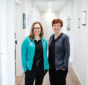 Two women standing in a hallway with a smiling expression on their faces