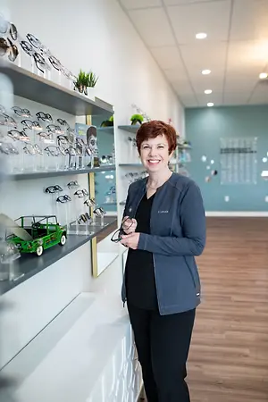 woman smiling standing in front of shelves with sunglasses on display