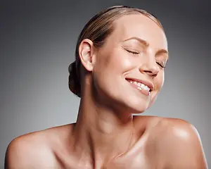 A woman smiling with her eyes closed and her head tilted to the left, possibly posing for a photo.