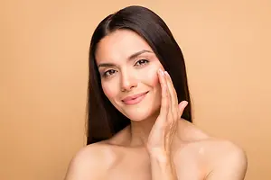 Close up of a woman smiling and touching her face.