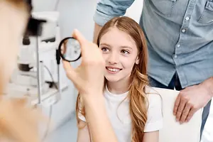 A young girl is having her eyes checked by an optometrist in a clinic.