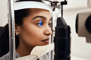 A woman is having her eyes examined by an optometrist using a slit lamp