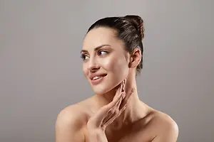 Close up of a woman smiling at the camera while holding her chin with one hand