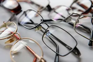A variety of eyeglasses with metal frames and transparent lenses placed on a white surface.