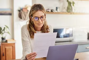 woman wearing glasses sitting in a chair reading a paper