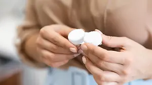 A person holding two contact lenses in their hands